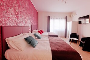 A hotel room with two beds, a TV, and a chair.