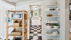A kitchen with white cabinets, a checkered floor, and shelves with dishes and glasses. - Quaint & Charming 2nd Row Beach House - Large Screened Porch - Steps to the Beach (Folly Beach)