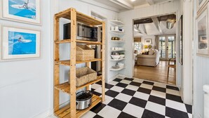A hallway with a checkered floor, wooden shelves with baskets, and a microwave. - Quaint & Charming 2nd Row Beach House - Large Screened Porch - Steps to the Beach (Folly Beach)
