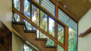 Un escalier en bois avec une personne assise sur une petite banquette rembourrée.