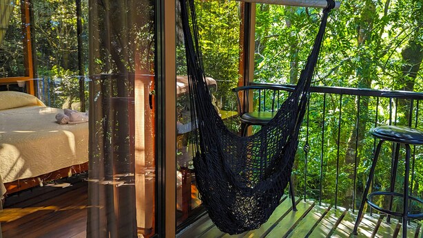 Un hamac sur un balcon, avec un lit et une table.