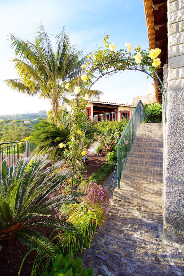 A stone staircase leading to a building with a view of a lush garden and distant landscape.