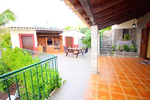 A patio with a tiled floor and a wooden table with chairs.