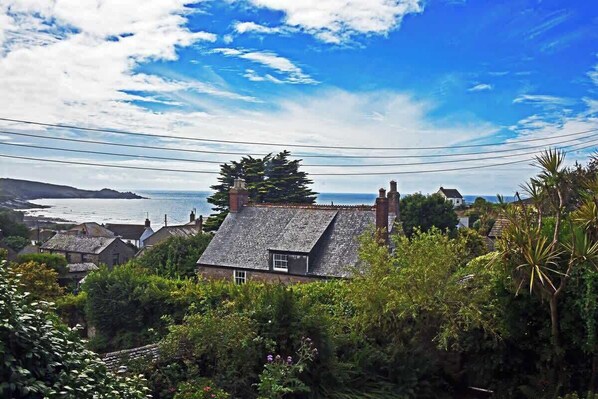 A coastal village with traditional stone houses, lush greenery, and a view of the sea.