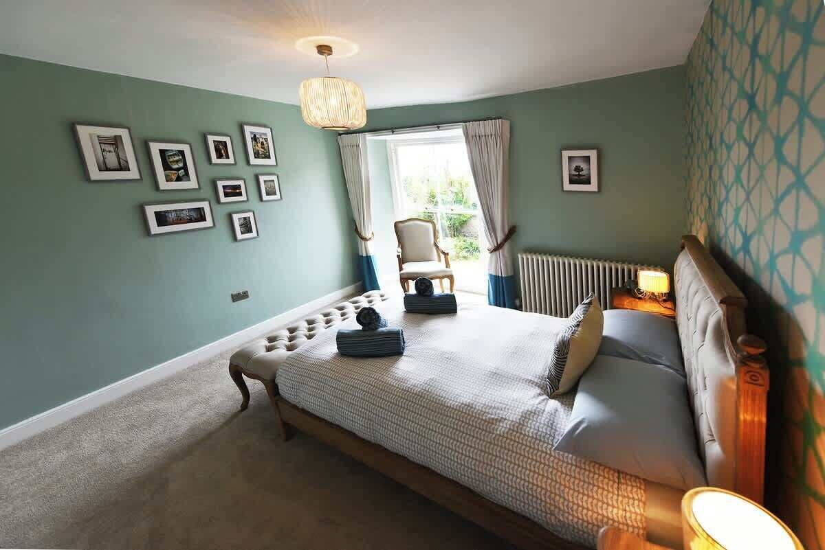 Ein Schlafzimmer mit einem Bett, einem Sessel, einem Heizkörper und einem Fenster mit Vorhängen.