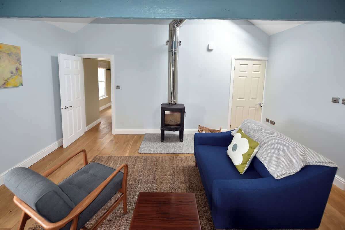 A living room with a blue sofa, a grey armchair, a wooden coffee table, a fireplace, and a rug.