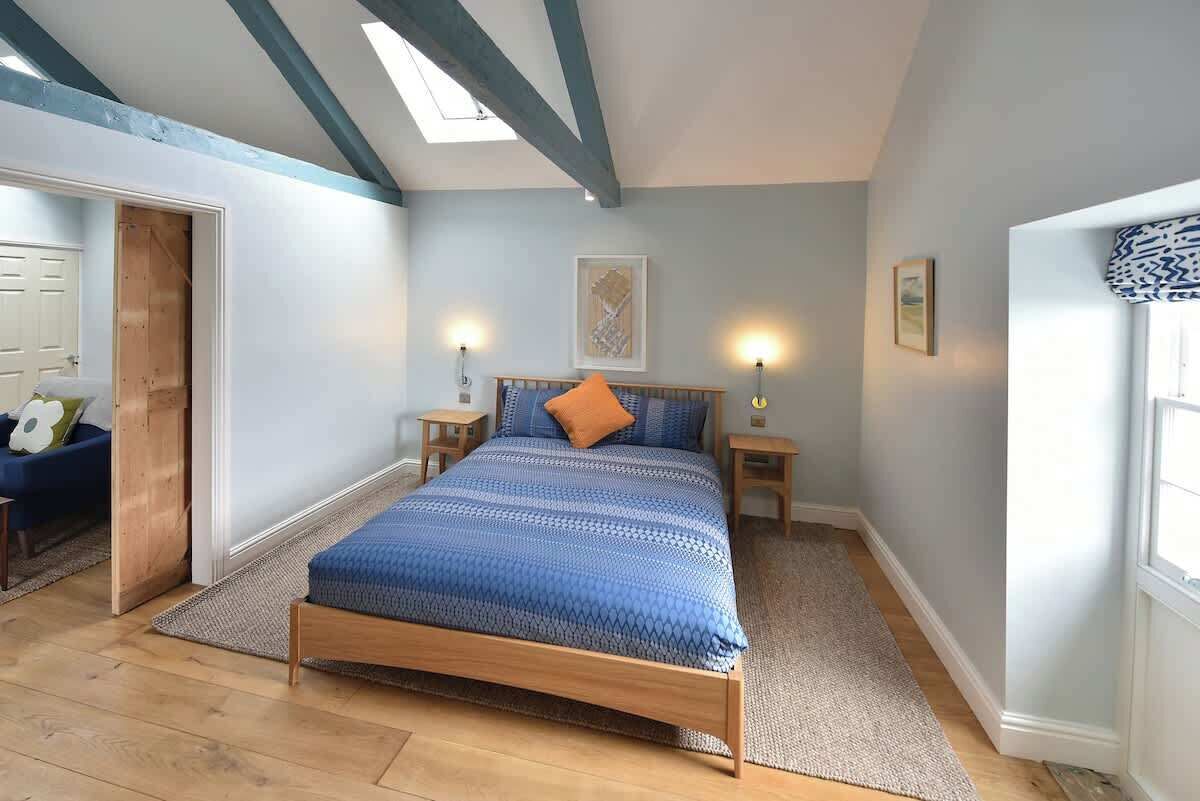 Ein Schlafzimmer mit einem hölzernen Bett, einem Oberlicht und Blick ins Freie.