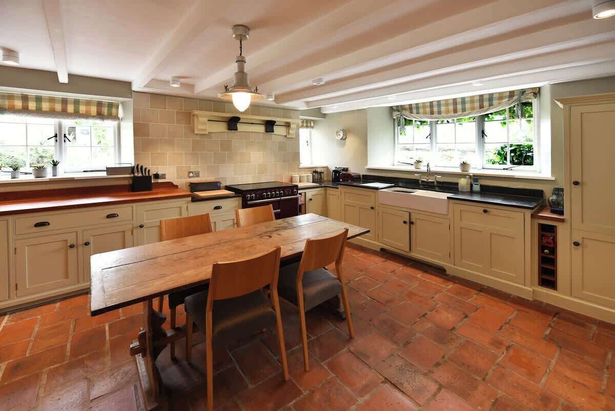 A spacious kitchen with a large wooden table, ample counter space, and a built-in oven.
