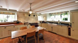 A spacious kitchen with a large wooden table, ample counter space, and a built-in oven. - Historical Churchtown House - Whole House (Perranuthnoe)