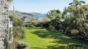 A stone building with a grassy yard and a view of the sea. - Historical Churchtown House - Whole House (Perranuthnoe)