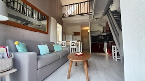 Un salon avec un canapé gris, une table basse en bois et un escalier menant à un niveau supérieur.
