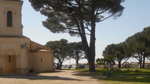 A historic building with a bell tower, surrounded by trees and a gravel path. - Spacious T2 duplex in a wooded residence 5 minutes from the beach and the center (Andernos-les-Bains)