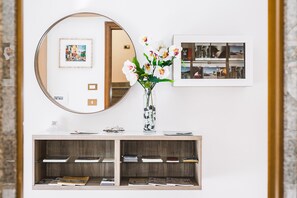 Une chambre moderne avec un miroir rond, un vase de fleurs et un tableau encadré au mur.