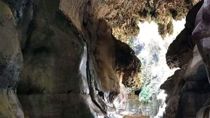 A cave with a narrow passage leading to a small pool of water.