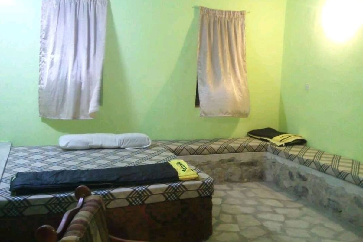 A room with a bed, a bench, and a small sitting area.