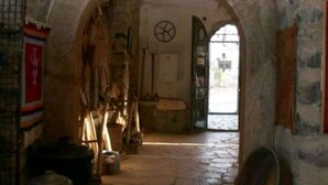 An arched stone corridor with rustic furnishings and a stone floor.