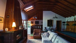 Ein gemütliches Wohnzimmer mit Kamin, Ledersofa und Holzbalkendecke.