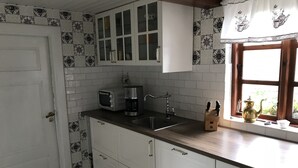 A kitchen with white cabinets, a coffee maker, a toaster, and a window with a view of greenery.
