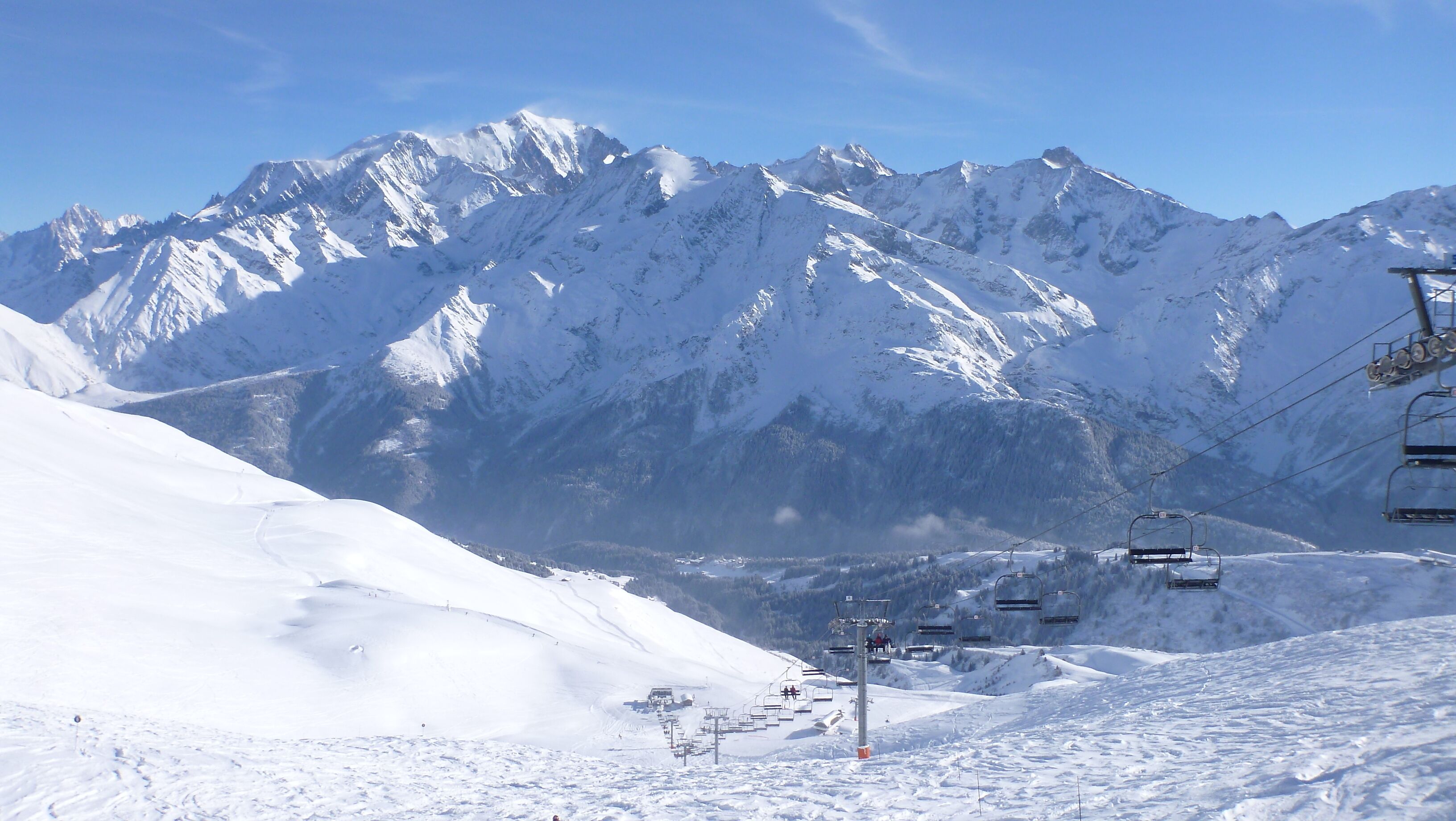 Ein mit Schnee bedeckter Berg mit Seilbahnen und blauem Himmel.