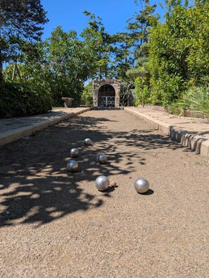 Un sentier bordé d’objets sphériques, un arc en pierre et une végétation luxuriante tout autour.
