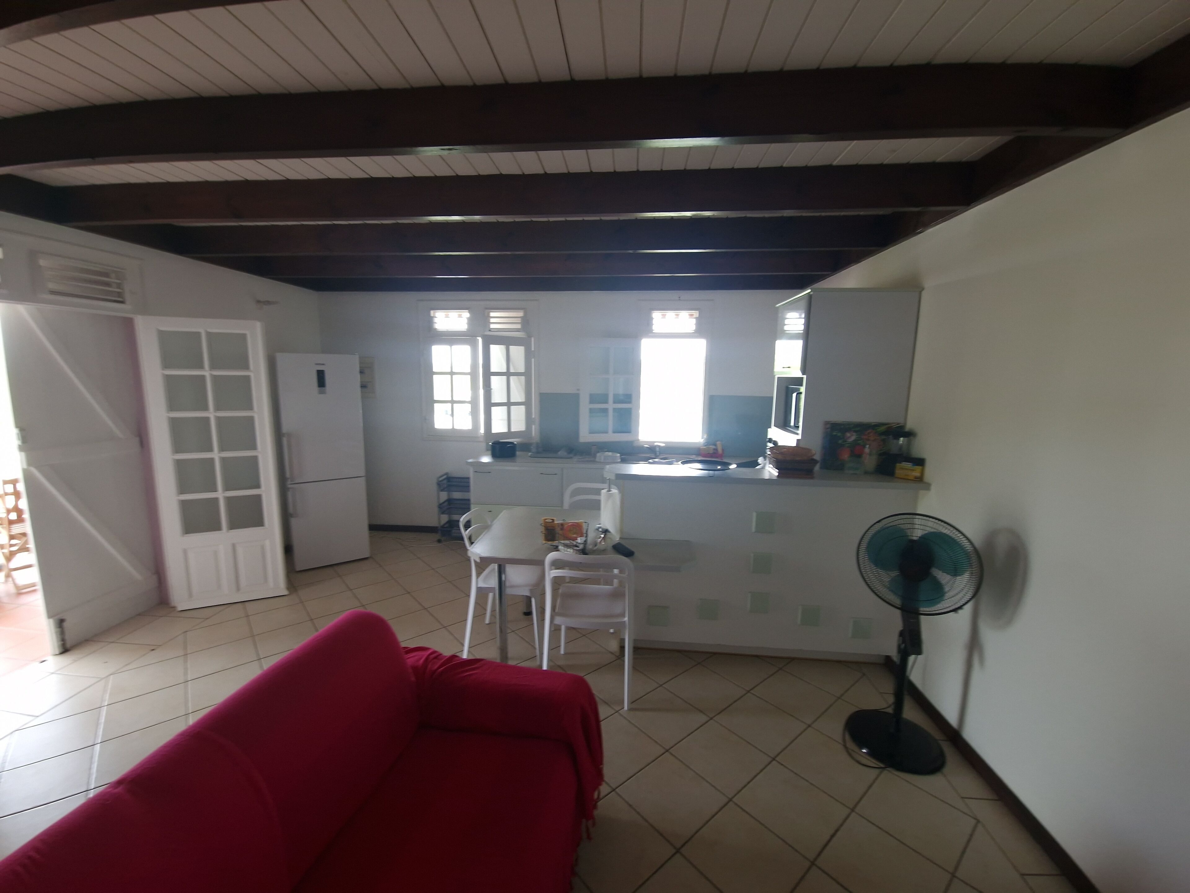 A compact living space with a kitchenette, a dining area, and a red sofa.