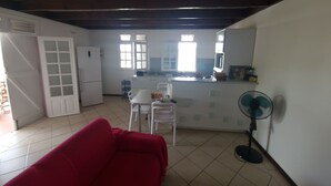 Un espacio habitable compacto con kitchenette, comedor y un sofá rojo.