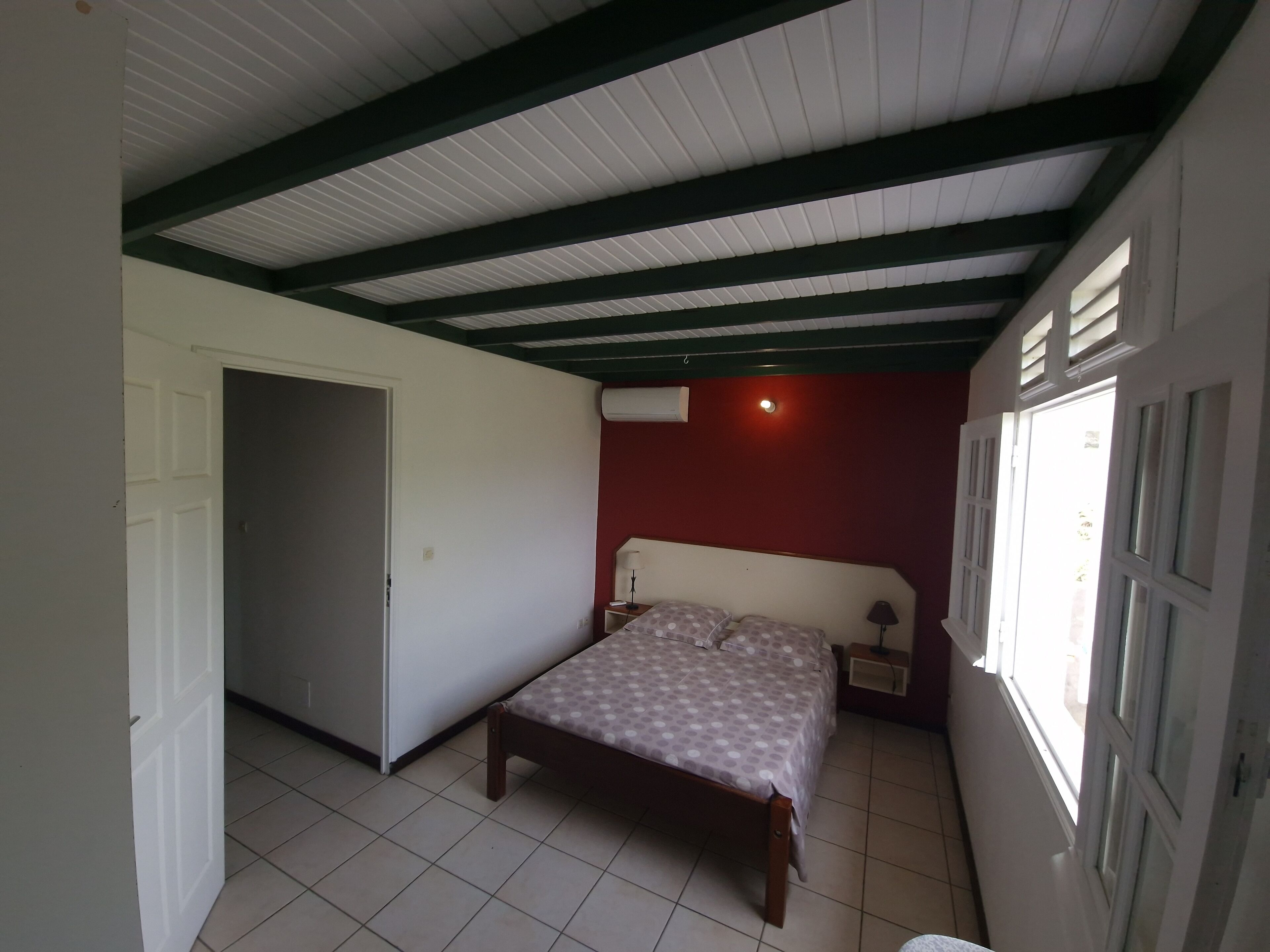 A bedroom with a bed, a nightstand, a window, and a door.