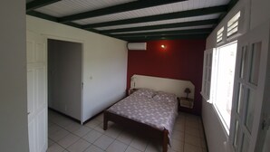 Un dormitorio con cama, mesita de noche, ventana y puerta.