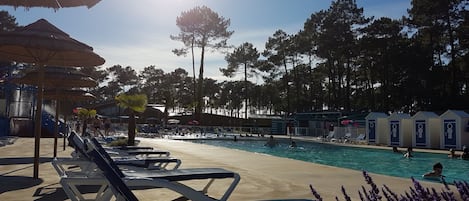 A pool area with lounge chairs, a water slide, and a row of cabins.