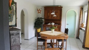 Un coin repas avec une table et des chaises en bois, une plante en pot et un meuble.
