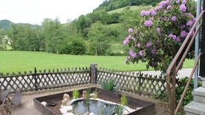 Un jardin avec un bassin en bois, une clôture en bois et un arbre en fleurs.