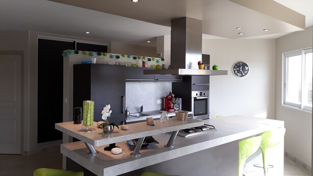 Una cucina moderna con isola centrale, sgabelli da bar e forno integrato.