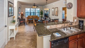 A spacious kitchen with granite countertops, a dishwasher, and a dining area with a sofa and chairs. - Bella Piazza 912 - 234 (Davenport)