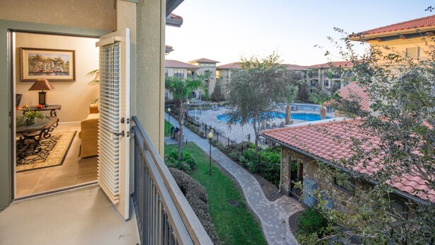 A balcony with a view of a swimming pool, a dining area, and a garden. - Bella Piazza 912 - 234 (Davenport)