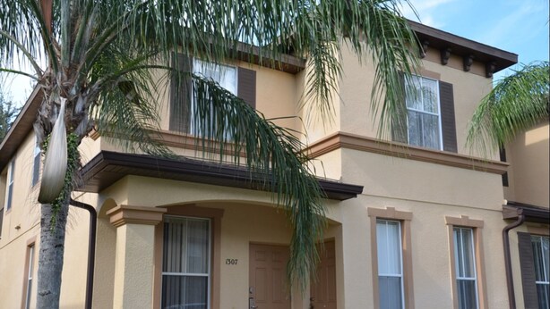 A two-story building with a beige facade, a balcony on the second floor, and a door marked with the number 1307. - Regal Palms Resort & Spa 1307 (Davenport)