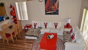 A living room with a dining area, a red coffee table, a patterned rug, and a painting on the wall. - Regal Palms Resort & Spa 1307 (Davenport)