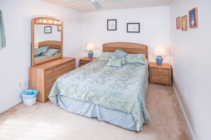 Un dormitorio con cama, dos mesitas de noche, un espejo y una lámpara fijada a la pared.