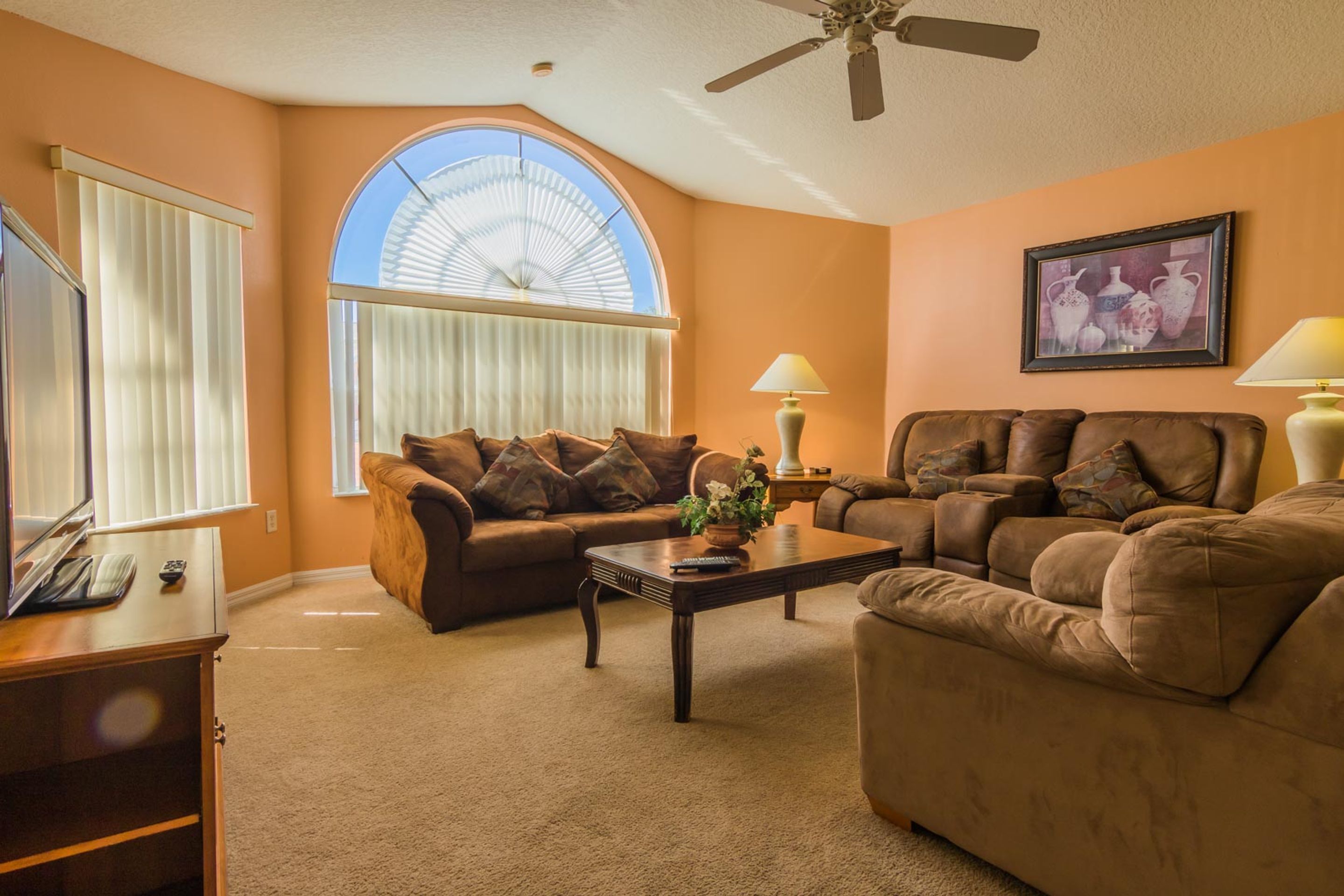 A living room with two brown leather sofas, a wooden coffee table, and a television on a wooden cabinet.
