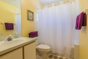 A bathroom with a sink, toilet, and shower curtain.