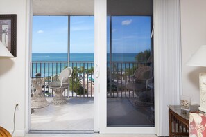 A balcony with wicker chairs and a view of the ocean.