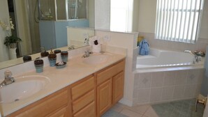 A bathroom with two sinks, a bathtub, and a shower.
