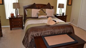 A neatly arranged bedroom with a bed, bedside tables, lamps, and a small rug.