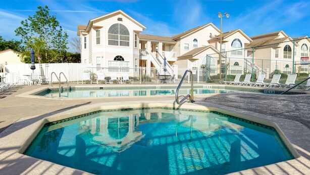 A swimming pool with a sunken center, surrounded by lounge chairs and a building with a staircase.