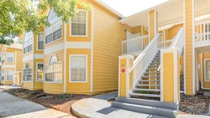 A yellow building with a white staircase and a small porch.