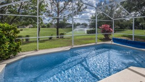 A swimming pool with a clear view of the surrounding landscape, including trees and a lawn. - Southern Dunes 2401 (Haines City)