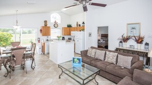 A spacious living area with a glass coffee table, brown sofa, and a dining area with wicker chairs. - Southern Dunes 2401 (Haines City)