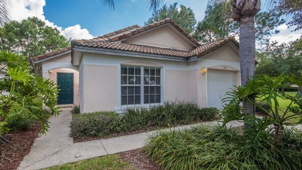 A single-story house with a tiled roof, a front door, and a garage. - Southern Dunes 2401 (Haines City)