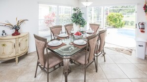 A dining area with a glass-top table, six chairs, and a buffet cabinet. - Southern Dunes 2401 (Haines City)