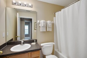 A bathroom with a sink, mirror, and toilet. There are towels hanging on the wall and a shower curtain. - Sandy Ridge 160 (Davenport)