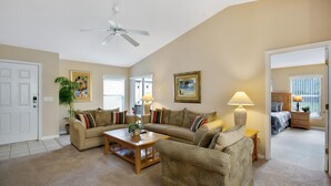 Ein Wohnzimmer mit Deckenventilator, zwei Sofas, einem Couchtisch und einer Lampe.
